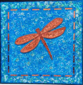 Blum dragonfly in orange with blue background