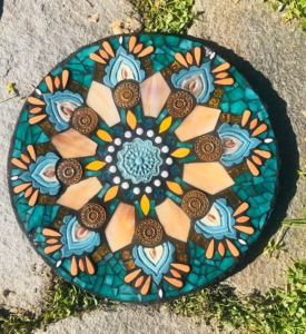 A round mosaic tile sitting on top of a cement ground.