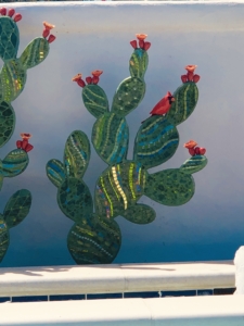 A painting of cactus with red flowers on it.