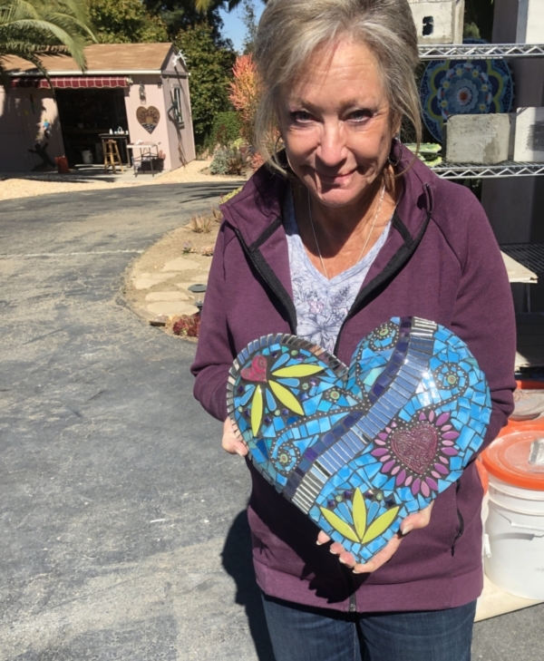 A woman holding up a heart shaped bag.