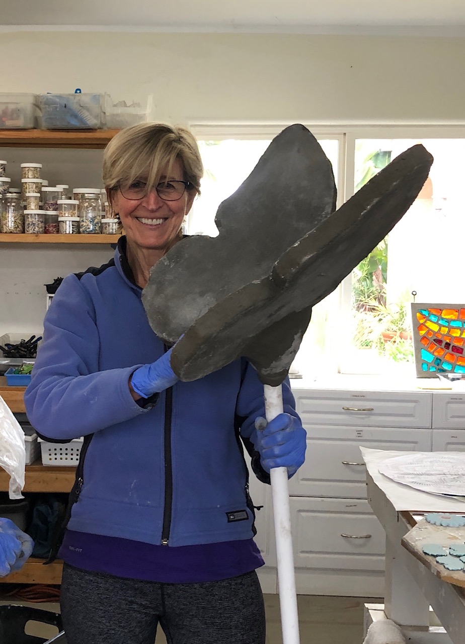 A woman holding up a large metal object.