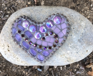 A purple heart sitting on top of a rock.