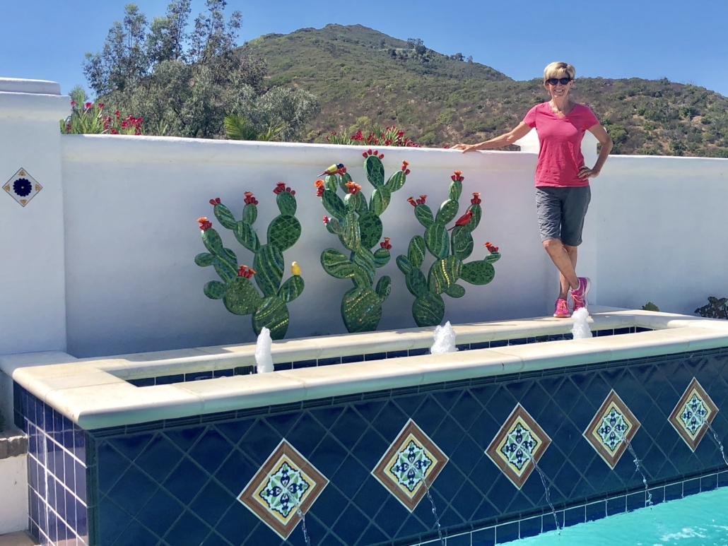A woman standing next to a pool with cactus plants.
