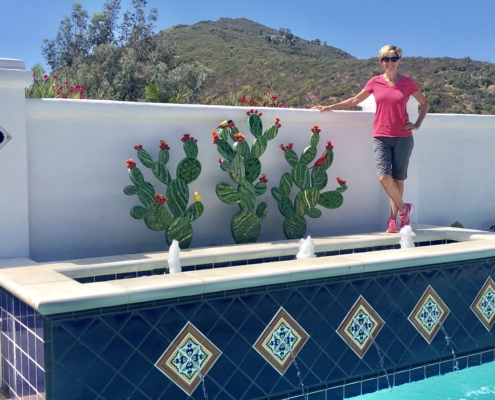 A woman standing next to a pool with cactus plants.