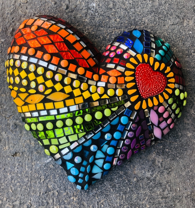 A heart shaped rock with many colors of paint.