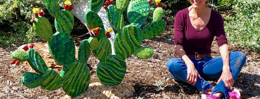 A woman kneeling down next to a cactus.