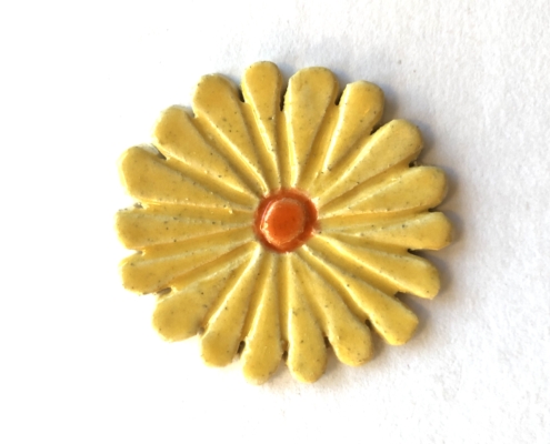 A yellow flower with orange center on white background.